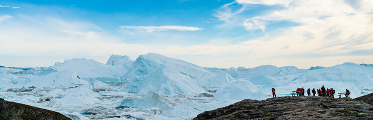 Wall Mural - Icebergs in arctic landscape nature with travel tourists in Greenland. People looking at amazing view of Greenland Icebergs in Ilulissat icefjord affected by climate change and global warming.