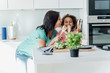 © Westend61 - Mother and daughter cooking in kitchen together playing with wooden spoons