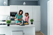 © Westend61 - Mother and daughter cooking in kitchen together