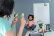 © Westend61 - Mother showing broccoli to daughter in kitchen