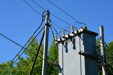 Electricity pylon with transformer and wires against a blue sky. The concept of electricity.