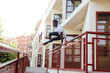 © Westend61 - Young man jumping across a fence in the city