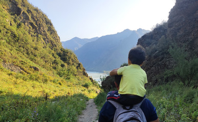 Mountain landscape with a child on the shoulders of a man. The concept of a healthy lifestyle, parental care and love