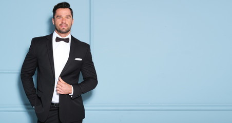 Elegant man in black classic suit posing in nice studio.