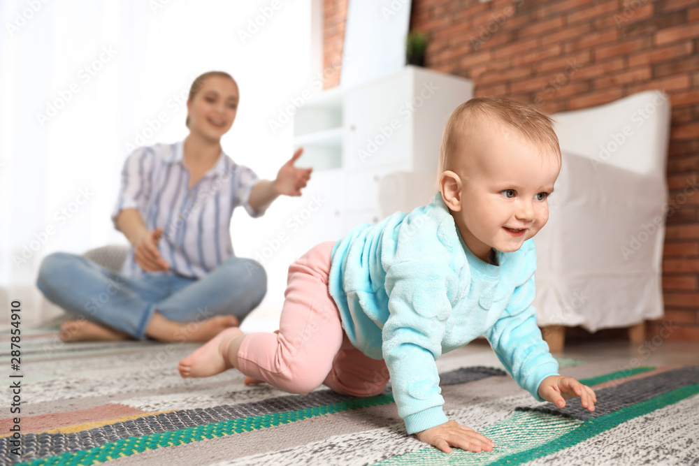 Mother watching her baby crawl on floor at home - obrazy, fototapety, plakaty 