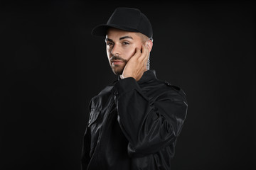 Wall Mural - Male security guard in uniform using radio earpiece on dark background