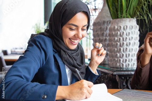 Fotomural Happy businesswoman taking notes in coffee shop