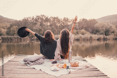Cuadros en Lienzo Two women friends having picnic in autumn forest near lake.
