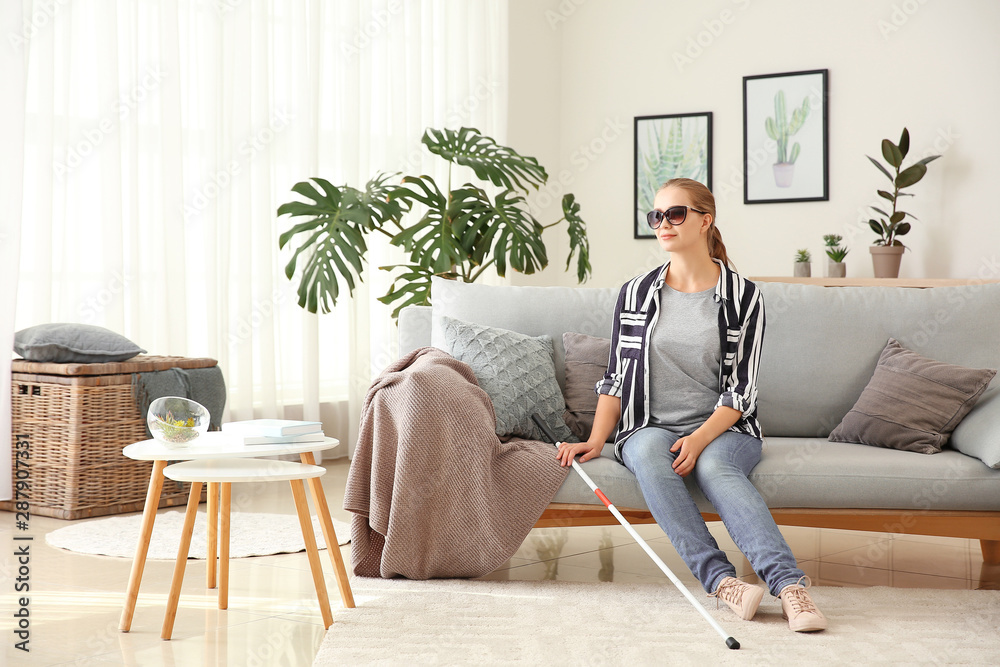 Young blind woman sitting on sofa at home