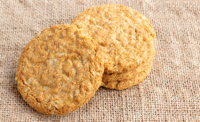 Wall Mural - Homemade oat and wholemeal biscuits isolated on brown sackcloth background. Its are a nutrient-rich food associated with protein, fiber and no artificial flavours or colour added.