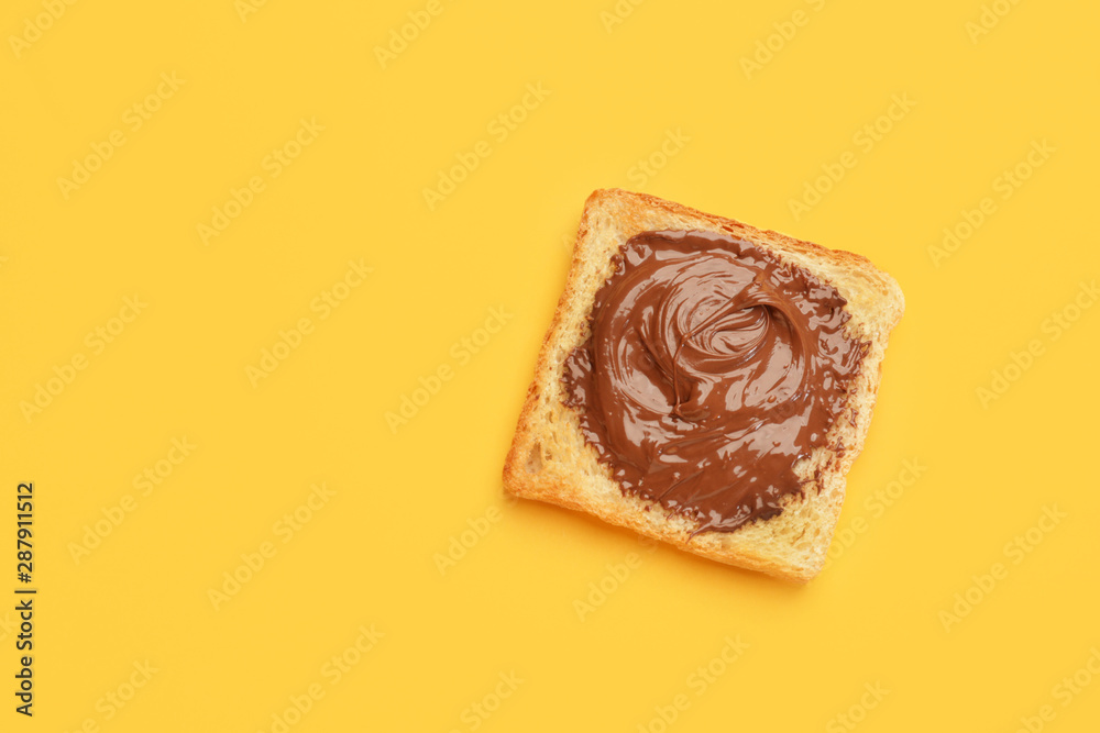 Tasty toasted bread with chocolate paste on color background