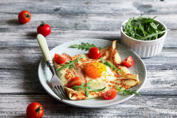 Wall Mural - Crepes with eggs, cheese, arugula leaves and tomatoes. Galette complete. Traditional dish galette sarrasin.