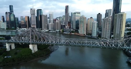 Sticker - Story bridge across Brisbane river in front of Brisbane city CBD high-rise towers and waterfront in aerial flying over water.