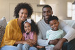 © wavebreak3 - Happy African American family sitting on sofa and looking at