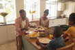 © wavebreak3 - Happy African American family having food at dining table