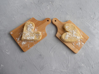 Two heart-shaped muffin blanks on small wooden planks against a gray concrete background.