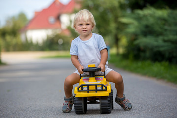 Sticker - Sweet toddler boy, riding plastic toycar on the street in quiet neighborhood