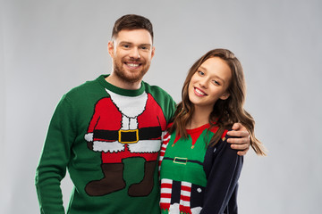 christmas, people and holidays concept - portrait of happy couple at ugly sweater party