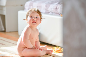 child is sitting in the bedroom. baby boy crawling on bed. little child playing in white sunny bedro