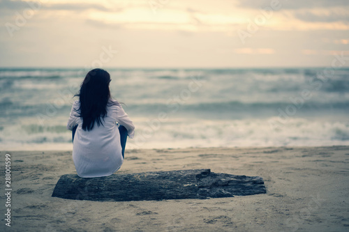 Fotografía Lonely woman sitting on a wooden bridge sunset