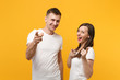 © ViDi Studio - Funny young couple two friends guy girl in white empty blank design t-shirt posing isolated on yellow orange background. People lifestyle concept. Mock up copy space. Pointing index fingers on camera.