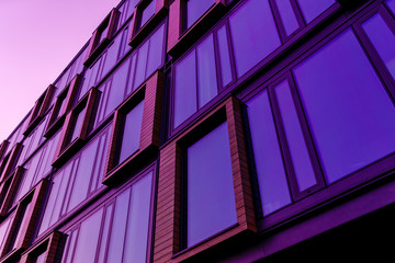 Wall Mural - Modern office building in the evening. Facade purple mirror