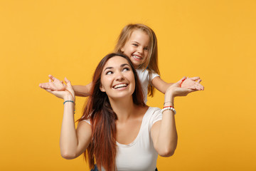 Woman in light clothes have fun with cute child baby girl 4-5 years old. Mommy little kid daughter isolated on yellow background studio portrait. Mother's Day love family parenthood childhood concept.