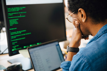 Focused male it professional using laptop while sitting in creative workplace