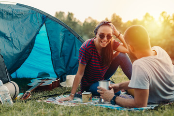 Wall Mural - friends on camping outdoor by the river enjoying coffee