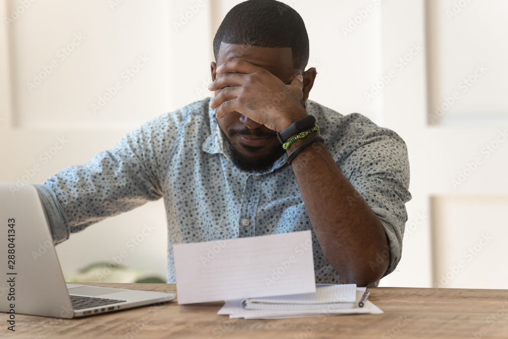 Stressed upset african american reading bad news in letter. - obrazy, fototapety, plakaty 