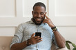 © fizkes - Happy smiling young african american guy holding cell phone.
