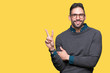 © Krakenimages.com - Young handsome man wearing glasses over isolated background smiling with happy face winking at the camera doing victory sign. Number two.