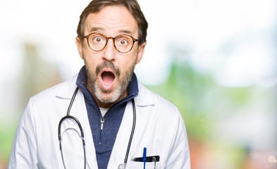 Poster - Handsome middle age doctor man wearing medical coat afraid and shocked with surprise expression, fear and excited face.