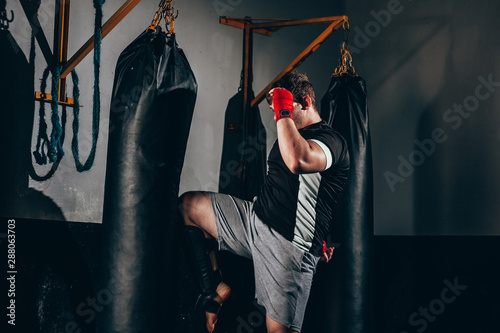 фотографія Muscular kickbox fighter exercising with punch bag at the gym
