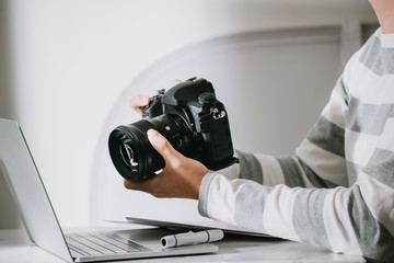 Fototapete - male photographer holding digital camera above the desk in his photo studio