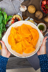 Orange baked squash, woman hands holds grilled pumpkin in frying pan. Vegetarian lunch and vegan food