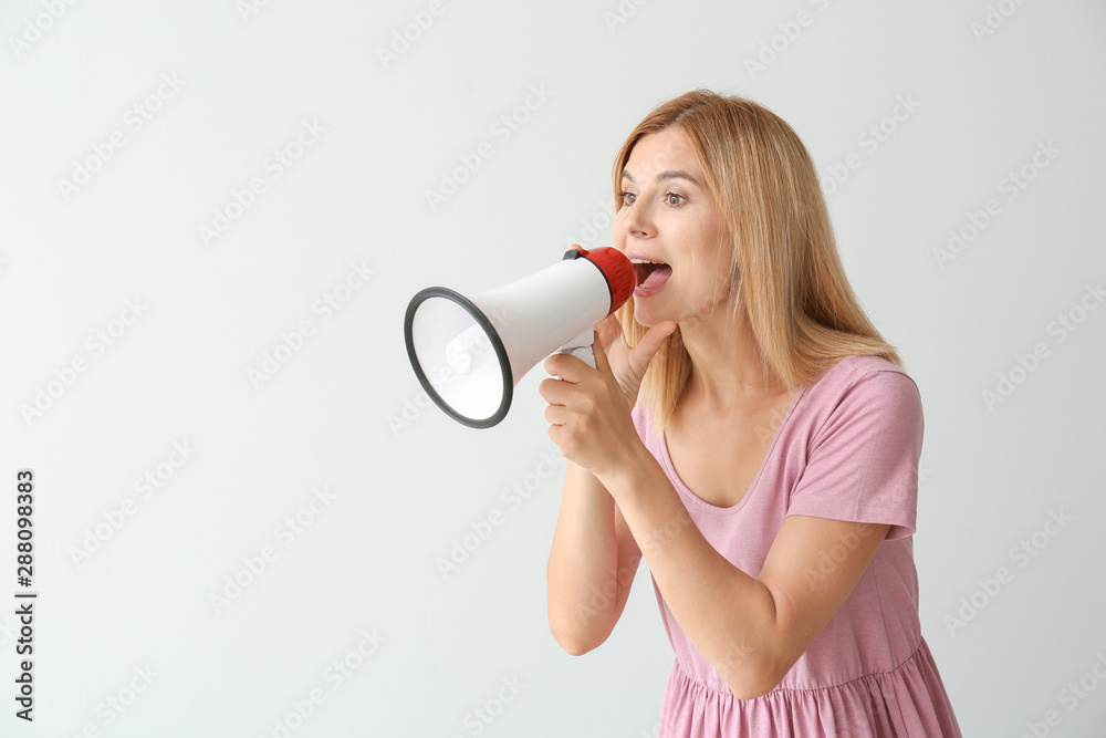 Screaming woman with megaphone on light background