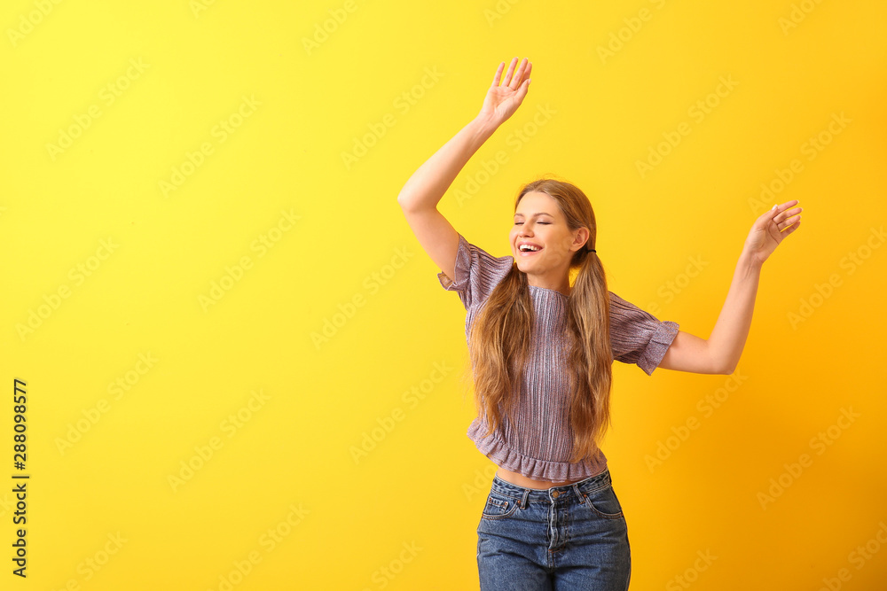 Beautiful young woman dancing against color background