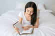 © Pixel-Shot - Beautiful young woman reading book in bedroom