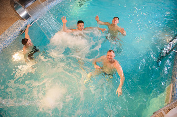 Wall Mural - top view of 4 men relaxing in swimming pool in a spa centre