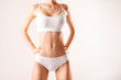 © Evrymmnt - Close up shot of unrecognizable fit woman in lingerie isolated on white background. Torso of slim attractive female with flat belly in white underwear. Copy space for text.