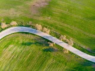 Aerial view of green summer grass with a road. Captured from above with a drone