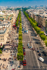 Great aerial portrait view of the famous Avenue des Champs-Élysées in Paris on a nice sunny day with a blue sky at the horizon. People walking along the shops or crossing at the crosswalk.