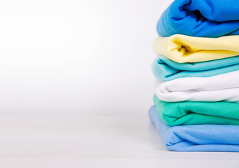 Wall Mural - Colorful stack of cotton clothes white empty copy space background.