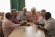 © WavebreakMediaMicro - Group of senior people playing cards in living room