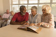 © WavebreakMediaMicro - Group of senior people looking at photo album at nursing home