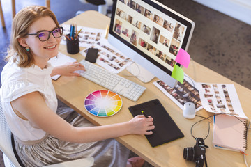 Female graphic designer working on graphic tablet at desk in office