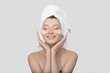 © Alena - woman is laughing with cream on her face and a towel on her head. White background. Skin care concept