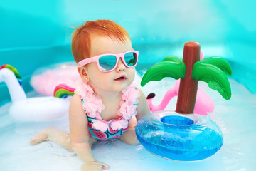 cute happy baby girl having fun in kid pool, summer vacation