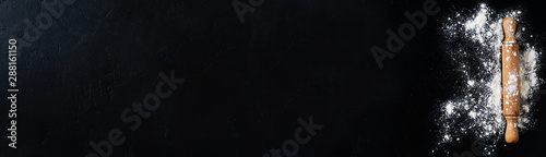 Fotografía Rolling pin with flour on dark black baking background, top view, copy space for text, menu, recipe